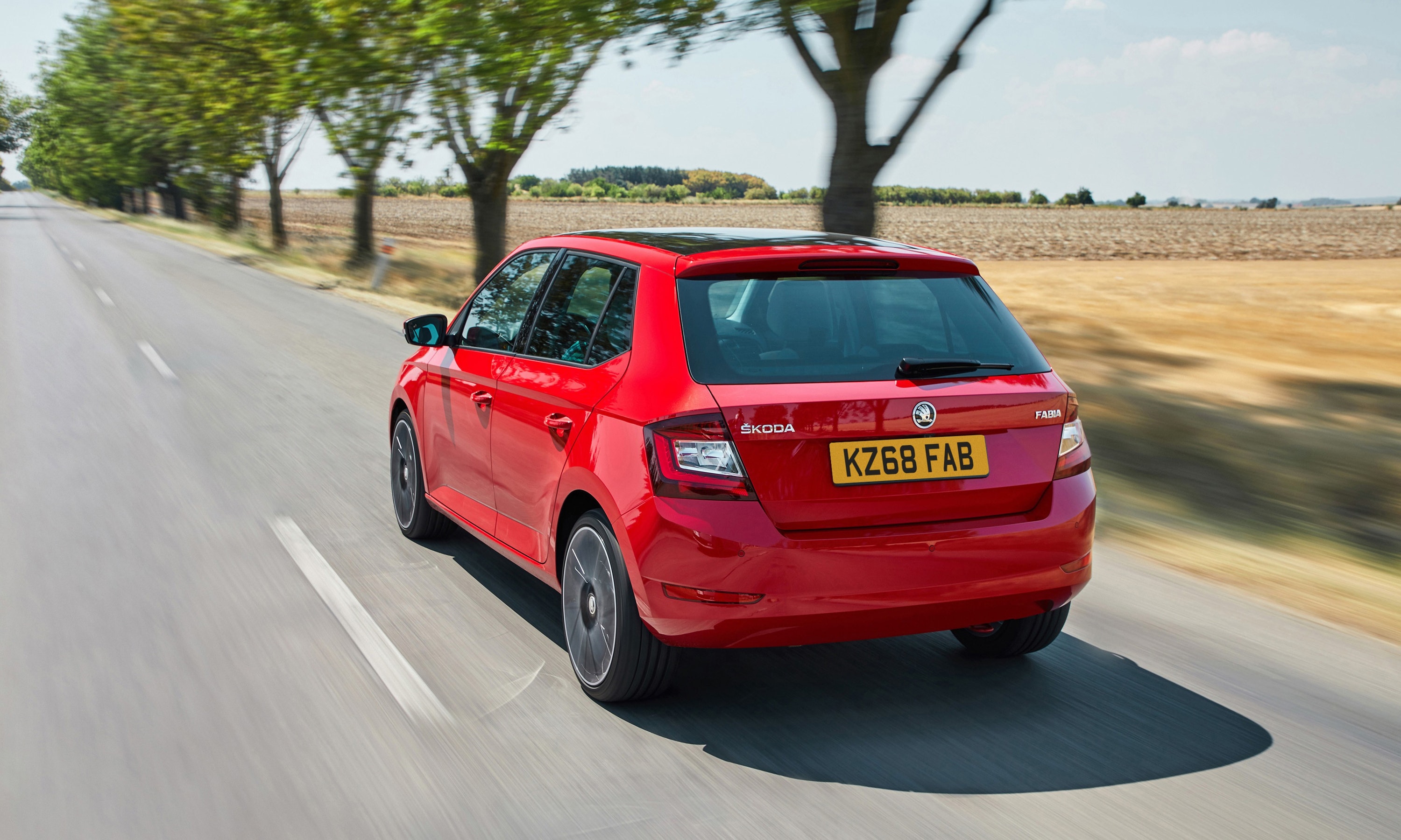 Rear view of a red Skoda Fabia driving on a road